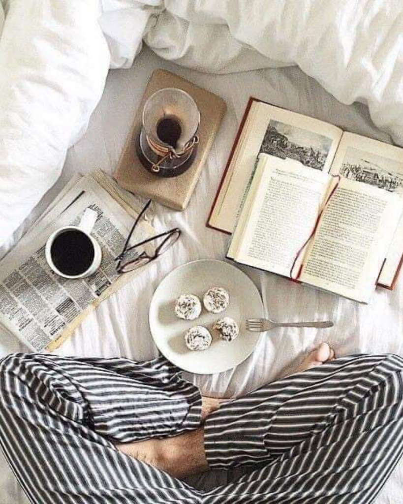 Photo d'une personne assise avec 2 livres ouverts, une tasse de café et son petit-déjeuner