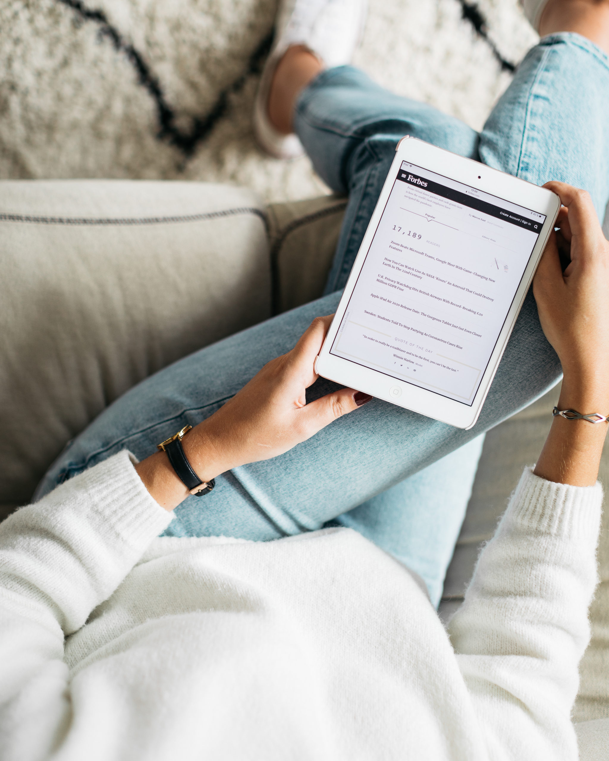 Personne assise sur un canapé avec une tablette à la main