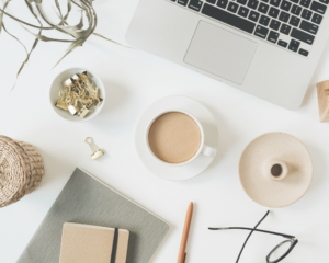 Ordinateur posé sur une table avec un carnet et un café à côté