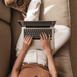 Photo d'une personne qui est assise sur son canapé avec un ordinateur portable sur les genoux