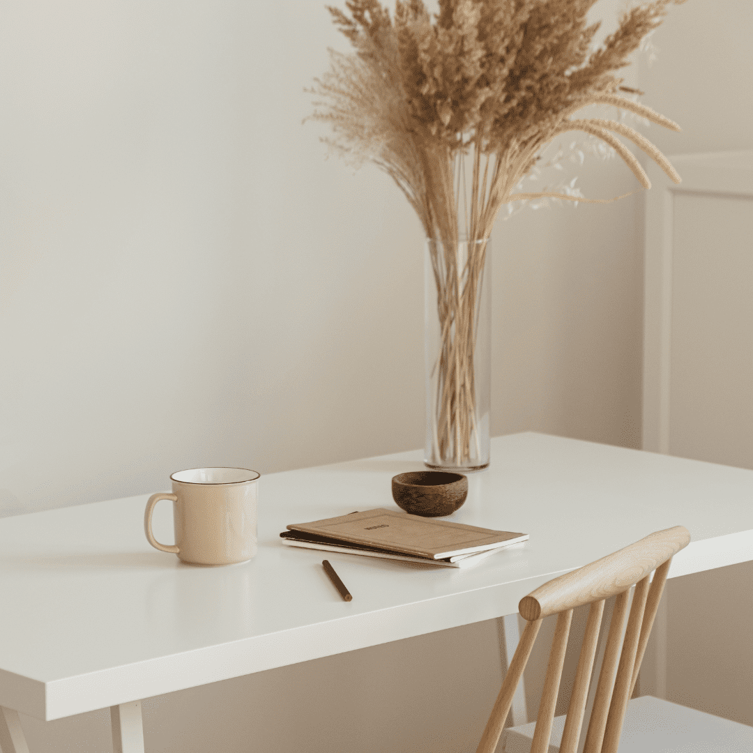 Photo d'un bureau avec un cahier, une tasse et un vase avec des fleurs