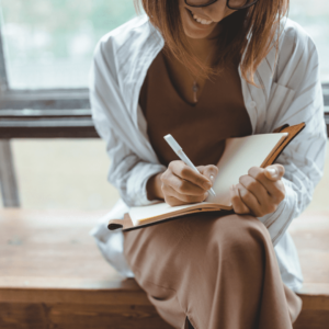 Une femme assise sur un banc en train d'écrire dans son journal