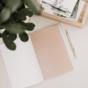 Un carnet ouvert posé sur un bureau avec un stylo or à côté