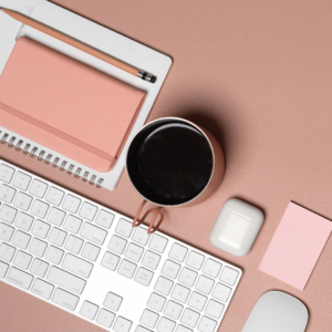 Une tasse de café est posée à côté d'un clavier d'ordinateur et un carnet