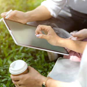 Femme assise dans un jardin qui est en train de consulter sa tablette